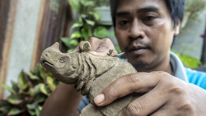 Perajin menyelesaikan pesanan ukiran kayu badak jawa di Ujung Jaya, Pandeglang, Banten, Sabtu (29/1/2022). Ukiran badak jawa tersebut dijual dengan harga Rp80 ribu hingga Rp400 ribu per buah tergantung jenis bahan dan ukuran. ANTARA FOTO/Muhammad Adimaja/wsj.