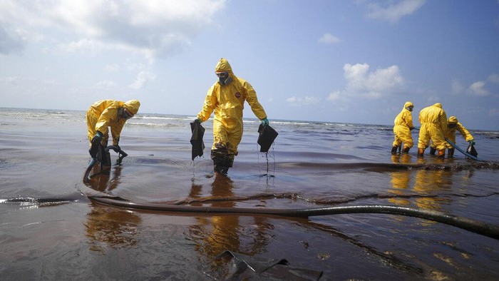 Workers carry out a clean-up operation on Mae Ramphueng Beach after a pipeline oil spill off the coast of Rayong province in eastern Thailand, Saturday, Jan. 29, 2022, At least 20 tons of oil leaked Tuesday night from an undersea hose at an offshore mooring point of the Star Petroleum Refining Co. used to load tankers, and despite efforts to disperse or contain it, some reached the beach Saturday morning, while a large slick remains at sea. (AP Photo/Nava Sangthong)