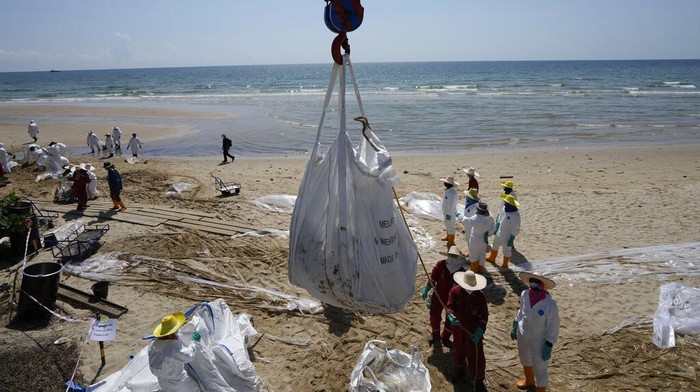 Gawat! Pantai di Thailand Tercemar Tumpahan Minyak Workers carry out a cleanup operation on Mae Ramphueng Beach after a pipeline oil spill off the coast of Rayong province in eastern Thailand, Sunday, Jan. 30, 2022. The governor of a province in eastern Thailand on Saturday declared a state of emergency after an oil slick washed up on a sand beach, shutting down restaurants and shops in a setback for the pandemic-hit tourism industry. (AP Photo/Sakchai Lalit)