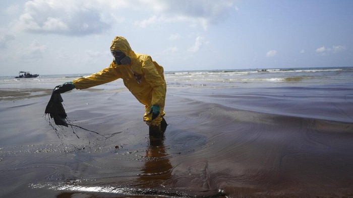 Workers carry out a clean-up operation on Mae Ramphueng Beach after a pipeline oil spill off the coast of Rayong province in eastern Thailand, Saturday, Jan. 29, 2022. At least 20 tons of oil leaked Tuesday night from an undersea hose at an offshore mooring point of the Star Petroleum Refining Co. used to load tankers, and despite efforts to disperse or contain it, some reached the beach Saturday morning, while a large slick remains at sea. (AP Photo/Nava Sangthong)