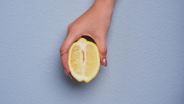 Cropped studio shot of an unrecognizable woman holding a lemon against gray background