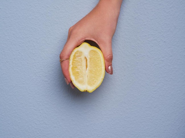 Cropped studio shot of an unrecognizable woman holding a lemon against gray background