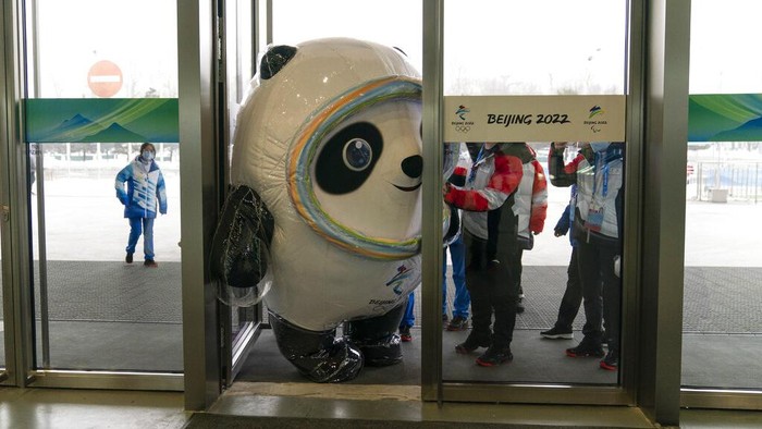 Inflated Beijing Games mascot, Bing Dwen Dwen, tries to squeeze through the door to enter the main media center at the 2022 Winter Olympics, Jan. 24, 2022, in Beijing. (AP Photo/Jae C. Hong)