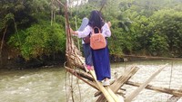 Sejumlah pelajar berangkat dan pulang sekolah dengan melewati jembatan yang hanya terdiri dari dua batang bambu di Cianjur.