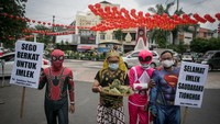 Warga dengan mengenakan kostum pewayangan dan superhero bertukar nasi berkat dengan kue keranjang di Klenteng Tien Kok Sie, Pasar Gede, Solo, Jawa Tengah, Senin (31/1/2022).