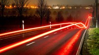 Foto eksposur panjang memperlihatkan lampu belakang mobil yang melaju di jalan raya, di pinggiran Frankfurt, Jerman, Selasa dini hari, (28/12/2021)