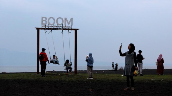 Wisatawan menikmati suasana di Pantai Boom, Banyuwangi, Jawa Timur, Selasa (1/2/2022). ANTARA FOTO/Budi Candra Setya.