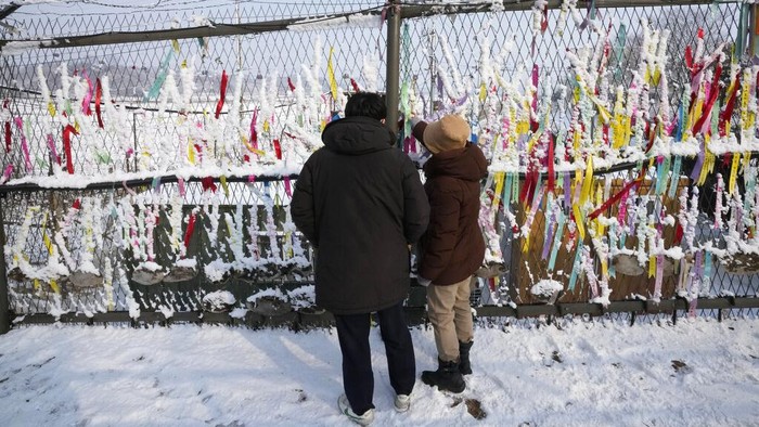 Potret Perayaan Imlek di Perbatasan Korsel-Korut People read messages on ribbons placed on a barbed wire fence, wishing for the reunification of the two Koreas, as they visit the Imjingak Pavilion near the border with North Korea, to celebrate the Lunar New Year in Paju, South Korea, Tuesday, Feb. 1, 2022. (AP Photo/Ahn Young-joon)