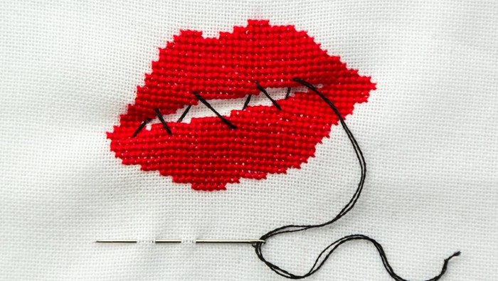 Lips embroidered with red thread on white fabric. Lips sewn with black thread.