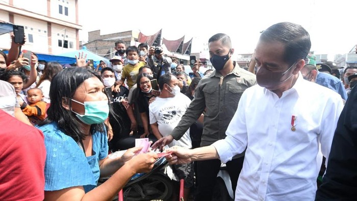 Aksi Jokowi Bagi-bagi Duit di Pasar Porsea Presiden Joko Widodo membagikan bantuan langsung tunai bagi para pedagang kaki lima dan warung di Pasar Porsea, Kabupaten Toba, Provinsi Sumatera Utara, pada Rabu, (2/2/2022).