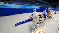 Pekerja dengan peralatan pelindung berjalan melalui Stadion Indoor Nasional di Olimpiade Musim Dingin 2022, Selasa, (1/2/2022), di Beijing. Loop tertutup ini akan memisahkan semua orang yang terlibat di dalam Olimpiade dari masyarakat China untuk menekan risiko infeksi. Diperkirakan 60.000 orang di dalam bubble harus menjalani testing setiap hari. (AP/Matt Slocum)