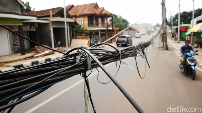 Pengendara melintas di Perempatan Embeh, Jalan Pangkalan II Bantargebang Kota Bekasi, Rabu (2/2/2022). Keberadaan kabel utilitas yang menjuntai di jalan dikeluhkan pengendara.