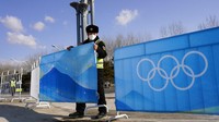 Seorang pekerja mendirikan penghalang di luar Pusat Media Utama pada Olimpiade Musim Dingin 2022. AP/Matt Slocum