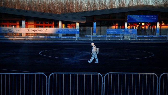 A worker wearing a protective suit sprays disinfectant at a screening checkpoint for arriving athletes at the 2022 Winter Olympics, Feb. 1, 2022, in the Yanqing district of Beijing. (AP Photo/Mark Schiefelbein)