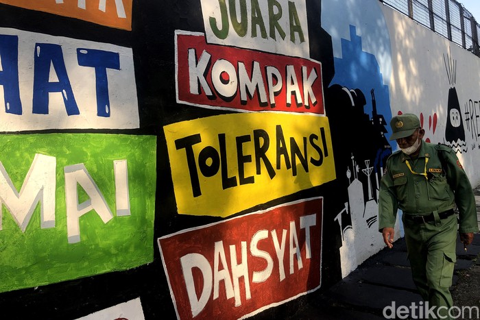 Warga berfoto di depan mural yang berisi pesan semangat untuk menjalani masa pandemi di Jl Tentara Pelajar, Jakarta, Selasa (1/2/2022).