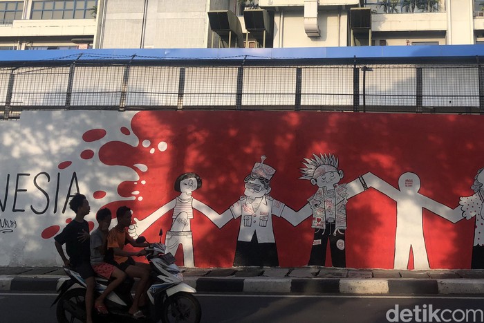 Semangat Kota di Dinding Kata Warga berfoto di depan mural yang berisi pesan semangat untuk menjalani masa pandemi di Jl Tentara Pelajar, Jakarta, Selasa (1/2/2022).