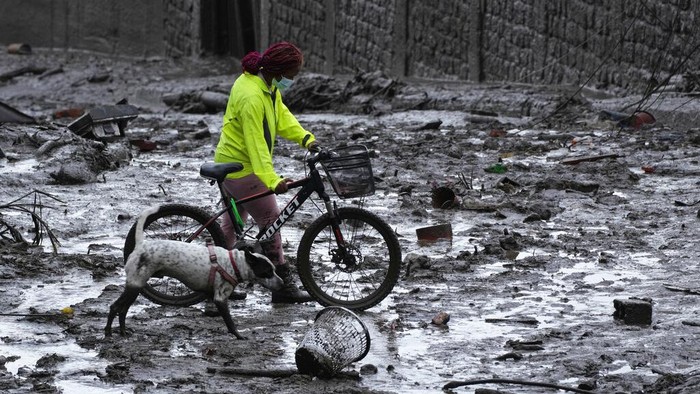 Rescue workers carry away the body of a victim after flash flooding triggered by rain filled up nearby streams that burst their containment mechanisms, collapsing a hillside and bringing waves of mud over homes in La Gasca area of Quito, Ecuador, Tuesday, Feb. 1, 2022. (AP Photo/Dolores Ochoa)