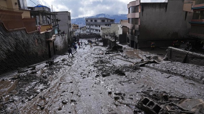 Rescue workers carry away the body of a victim after flash flooding triggered by rain filled up nearby streams that burst their containment mechanisms, collapsing a hillside and bringing waves of mud over homes in La Gasca area of Quito, Ecuador, Tuesday, Feb. 1, 2022. (AP Photo/Dolores Ochoa)