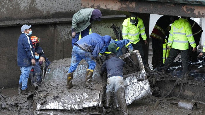 Rescue workers carry away the body of a victim after flash flooding triggered by rain filled up nearby streams that burst their containment mechanisms, collapsing a hillside and bringing waves of mud over homes in La Gasca area of Quito, Ecuador, Tuesday, Feb. 1, 2022. (AP Photo/Dolores Ochoa)