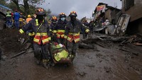 Petugas penyelamat membawa jenazah korban banjir bandang.