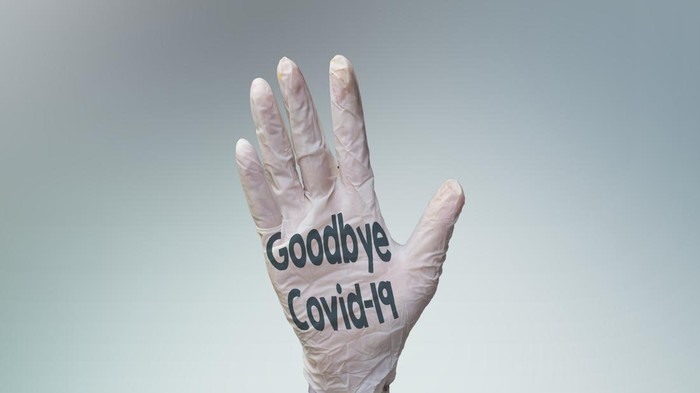 1216812367 goodbye covid-19 on palm hand wearing medical gloves