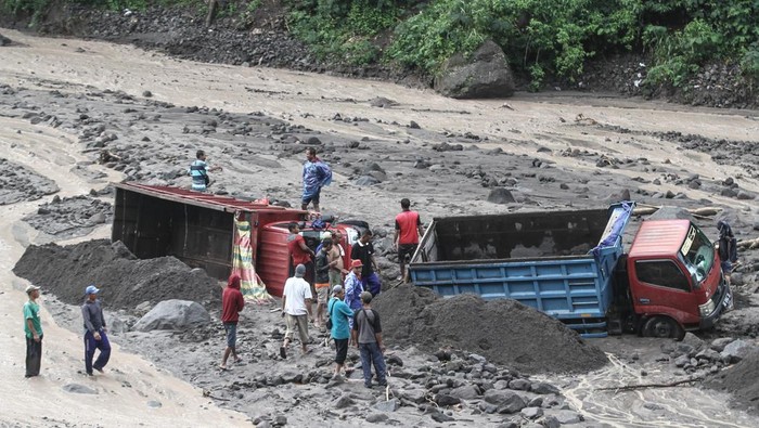 Warga membantu proses evakuasi truk yang terjebak banjir lahar di aliran Sungai Boyong, Sleman, DI Yogyakarta, Kamis (3/2/2022). Meski tidak ada korban jiwa dalam peristiwa tersebut namun sebanyak 24 truk penambang pasir terjebak banjir lahar Gunung Merapi di Sungai Boyong. ANTARA FOTO/Hendra Nurdiyansyah/YU