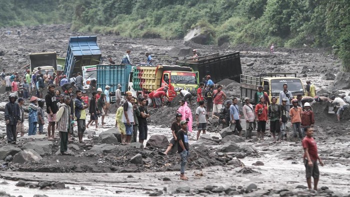 24 Truk Terjebak Banjir Lahar Gunung Merapi Warga membantu proses evakuasi truk yang terjebak banjir lahar di aliran Sungai Boyong, Sleman, DI Yogyakarta, Kamis (3/2/2022). Meski tidak ada korban jiwa dalam peristiwa tersebut namun sebanyak 24 truk penambang pasir terjebak banjir lahar Gunung Merapi di Sungai Boyong. ANTARA FOTO/Hendra Nurdiyansyah/YU
