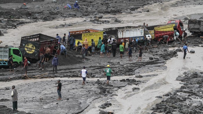 24 Truk Terjebak Banjir Lahar Gunung Merapi Warga membantu proses evakuasi truk yang terjebak banjir lahar di aliran Sungai Boyong, Sleman, DI Yogyakarta, Kamis (3/2/2022). Meski tidak ada korban jiwa dalam peristiwa tersebut namun sebanyak 24 truk penambang pasir terjebak banjir lahar Gunung Merapi di Sungai Boyong. ANTARA FOTO/Hendra Nurdiyansyah/YU