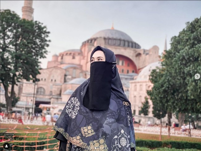 Kakak kandung Ria Ricis ini tampil memakai cadar ketika sedang liburan ke Istanbul, Turki. Selain sibuk mendakwah, ia mempunyai brand hijab yang bernama Merajutkisah. Dalam foto ini, ia mengenakan hijab motif yang dibentuk syari dan cadar hitam. Foto: Dok. Instagram @okisetianadewi.