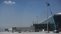 Pekerja menyelesaikan tahap akhir pembangunan seperti pemasangan lampu di apron bandara.