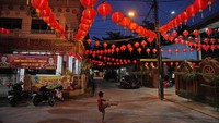 Anak kecil bermain di bawah naungan lampion, di halaman Kuil Hok Lay Kiong, Bekasi, Senin (31/1/2022). Lampion merupakan simbol pengharapan yang dinyalakan 2 pekan sejak Imlek hingga perayaan Cap Go Meh. (AP Photo/Dita Alangkara)