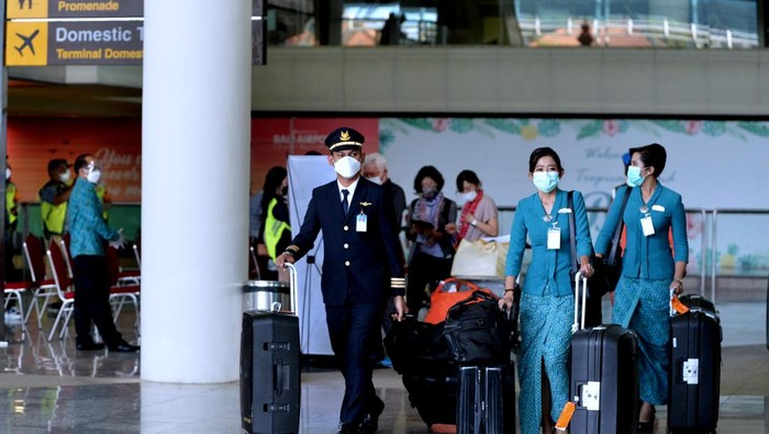 Petugas membantu penumpang pesawat maskapai penerbangan Garuda Indonesia dengan nomor penerbangan GA881 yang tiba di Bandara Internasional I Gusti Ngurah Rai, Badung, Bali, Kamis (3/2/2022). Penerbangan dengan rute Narita, Jepang menuju Bali yang mengangkut 12 orang penumpang tersebut menjadi penerbangan komersial rute internasional perdana yang dilayani Bandara I Gusti Ngurah Rai setelah pintu masuk internasional di bandara tersebut ditutup akibat pandemi COVID-19. ANTARA FOTO/Fikri Yusuf/YU