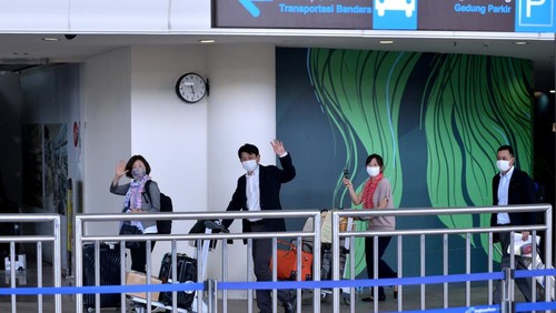 Petugas membantu penumpang pesawat maskapai penerbangan Garuda Indonesia dengan nomor penerbangan GA881 yang tiba di Bandara Internasional I Gusti Ngurah Rai, Badung, Bali, Kamis (3/2/2022).  Penerbangan dengan rute Narita, Jepang menuju Bali yang mengangkut 12 orang penumpang tersebut menjadi penerbangan komersial rute internasional perdana yang dilayani Bandara I Gusti Ngurah Rai setelah pintu masuk internasional di bandara tersebut ditutup akibat pandemi COVID-19. ANTARA FOTO/Fikri Yusuf/YU