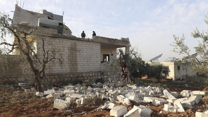 A child shows an empty bullet shell outside a destroyed house after an operation by the U.S. military in the Syrian village of Atmeh, in Idlib province, Syria, Thursday, Feb. 3, 2022. U.S. special forces carried out what the Pentagon said was a successful, large-scale counterterrorism raid in northwestern Syria early Thursday. Local residents and activists said civilians were also among the dead. (AP Photo/Ghaith Alsayed)
