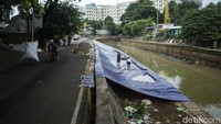 Pengendara melintas di sekitar jalan yang ambles.