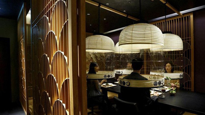 Cara Unik Restoran Jepang Lawan COVID-19 Hotel staff demonstrates 'Lantern Dining Experience', which enables diners to enjoy meals while protecting themselves against the spread of the coronavirus disease (COVID-19) at Hoshinoya Tokyo in Tokyo, Japan, February 2, 2022. The lantern-shaped transparent partitions are created by Japanβs traditional craftsman and guests staying at the hotel who pay 30,000 yen (about 260 USD) as venue charge can invite others to dine with them under the partitions. REUTERS/Kim Kyung-Hoon