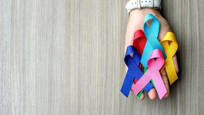 World cancer day (February 4). colorful awareness ribbons; blue, red, green, pink and yellow color on wooden background for supporting people living and illness. Healthcare and medicine concept