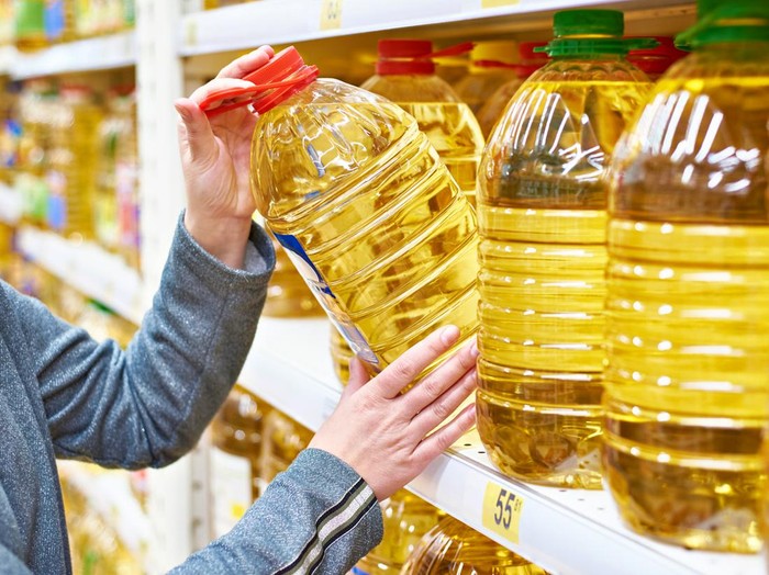 Big plastic bottle of olive oil in the hand of the buyer at the grocery store