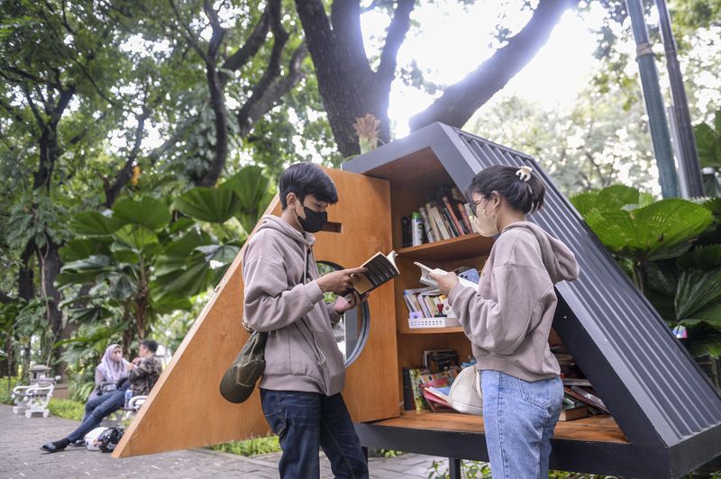 Dua orang pengunjung membaca buku di perpustakaan mini Taman Suropati, Jakarta, Sabtu (8/1/2022). Jakarta ditetapkan sebagai 'City of Literature' atau Kota Sastra Dunia dari 49 kota lain di dunia yang tergabung dalam jaringan kota kreatif jaringan kota kreatif dunia atau 'UNESCO's Creative City Network tahun 2021' oleh Badan Pendidikan dan Kebudayaan PBB (UNESCO). ANTARA FOTO/M Risyal Hidayat/rwa.