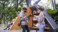 Dua orang pengunjung membaca buku di perpustakaan mini Taman Suropati, Jakarta.