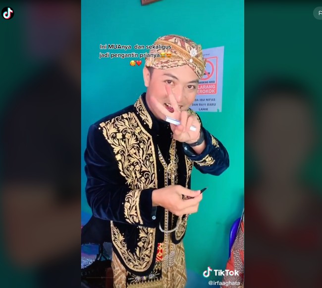 Akun TikTok @irfaaghata menjawab pertanyaan salah satu warganet soal apakah yang memakaikan paes dan sanggul juga pengantin pria. Terima kasih masukannya kak, tapi mohon maaf yang maes nyanggul itu yang pakai jilbab ungu😁, balasnya. Ia juga membalas komentar warganet yang mengatakan jika pasangan pengantin ini irit budget. Lebih tepatnya kalau kita bisa ngapain nggak wkkkk manfaatkan kemampuan kita dong😁, jawab MUA yang tinggal di Wonosobo, Jawa Tengah itu. Foto: Dok. Tangkapan layar akun TikTok @irfaaghata