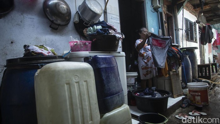 Seorang warga mencuci pakaian di kali Bambu Larangan, Cengkareng, Jakarta Barat, Rabu (2/2/2022). Kali berwarna hitam oekat ini masih digunakan oleh warga untuk mencuci pakaian, meski instalasi air bersih telah tersedia namun warga di sini tetap mencuci di kali.