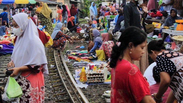 Pedagang menawarkan dagangannya kepada pembeli di pasar pinggir rel kereta api di Surabaya, Jawa Timur, Jumat (4/2/2022). Meskipun berbahaya, para pedagang di wilayah tersebut tetap berjualan di pasar itu setiap pagi. ANTARA FOTO/Patrik Cahyo Lumintu/Zk/tom.