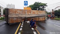 Badan truk tronton terguling di tengah jalan akibat ditabrak truk trailer.