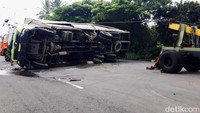 Truk muatan permen yang terguling ke bagian kanan badan jalan ini terlebih dulu dievakuasi dengan cara ditarik bagian atasnya menggunakan satu unit mobil derek. Kemudian satu unit mobil derek lainnya menahan bagian bawahnya dari sisi timur.
