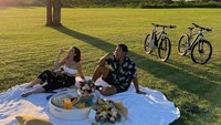 Saat piknik bersama pasangan muda ini membawa beberapa makanan, termasuk pizza. Ini momen mereka saat menikmati sepotong pizza di sebuah taman. Foto: Instagram @pschuldtz @darmamh