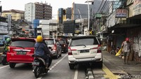 Seorang warga melintas di samping kendaraan yang parkir.