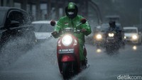 Para pengendara sepeda motor tetap melanjutkan perjalanan di tengah guyuran hujan deras.