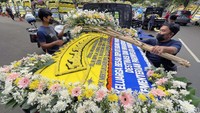 Petugas menurunkan karangan bunga yang terus datang.