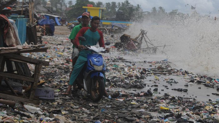 Pengendara roda dua melintasi tumpukan sampah yang terbawa ombak di Teluk Labuan, Pandeglang, Banten, Senin (7/2/2022). Sampah limbah rumah tangga tersebut terbawa oleh gelombang tinggi yang terjadi sejak beberapa hari terakhir di daerah itu. ANTARA FOTO/Muhammad Bagus Khoirunas/rwa.